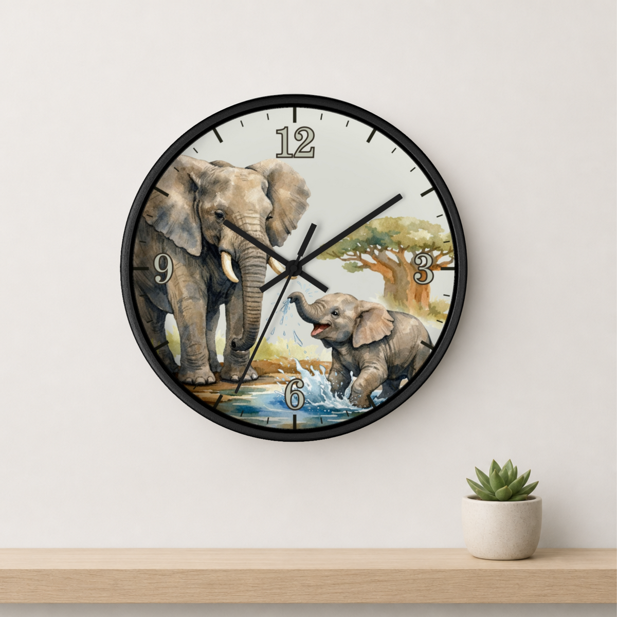 A round wall clock with a black frame and a safari-themed elephant illustration on the face, mounted on a light beige wall above a wooden shelf with a small potted succulent.