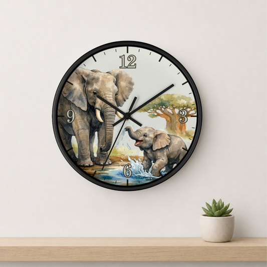 A round wall clock with a black frame and a safari-themed elephant illustration on the face, mounted on a light beige wall above a wooden shelf with a small potted succulent.