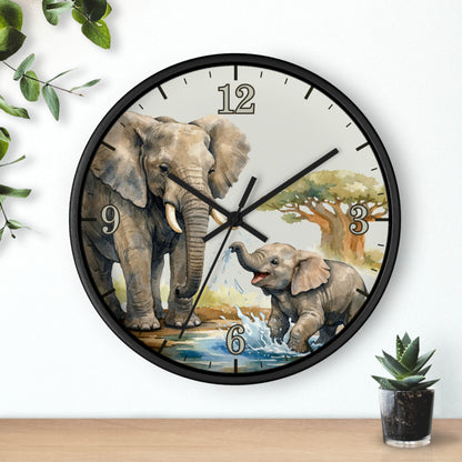 Round wall clock with a black frame and a printed elephant scene on the face, mounted on a white wall above a wooden surface with small green plants nearby.