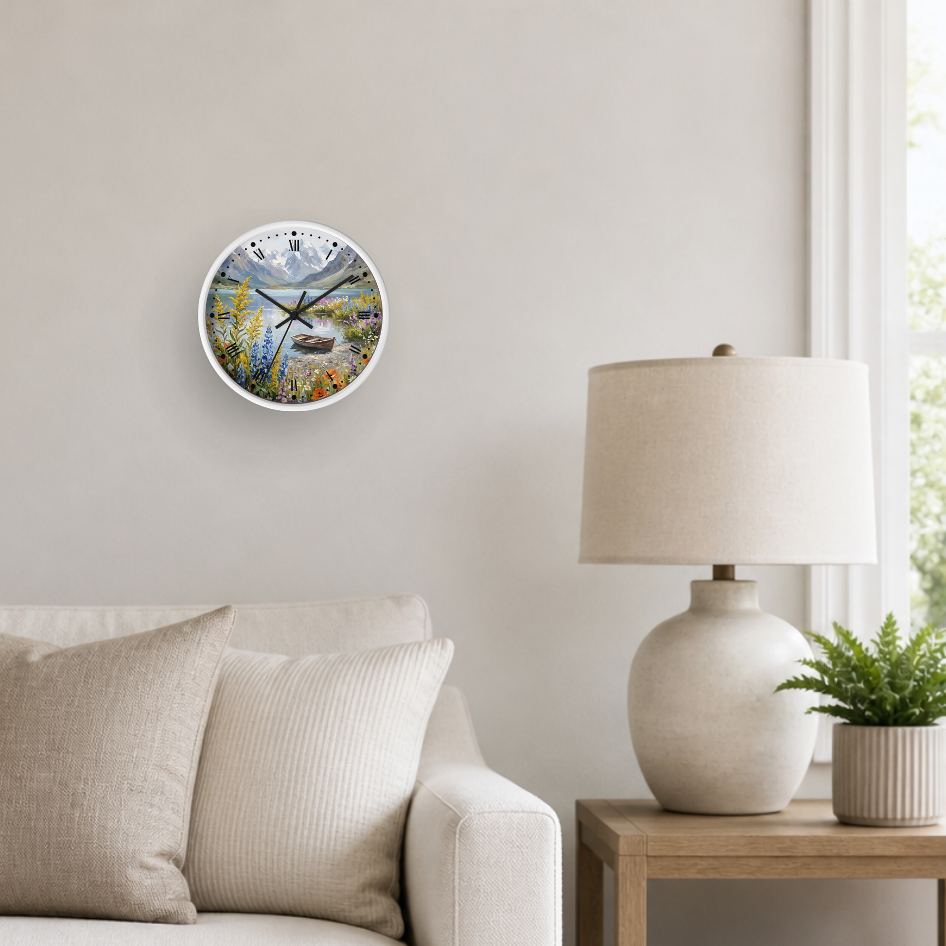 A round wall clock with a colorful landscape print of a lake and mountains, styled on a light beige wall above a sofa next to a table lamp and a small potted plant.