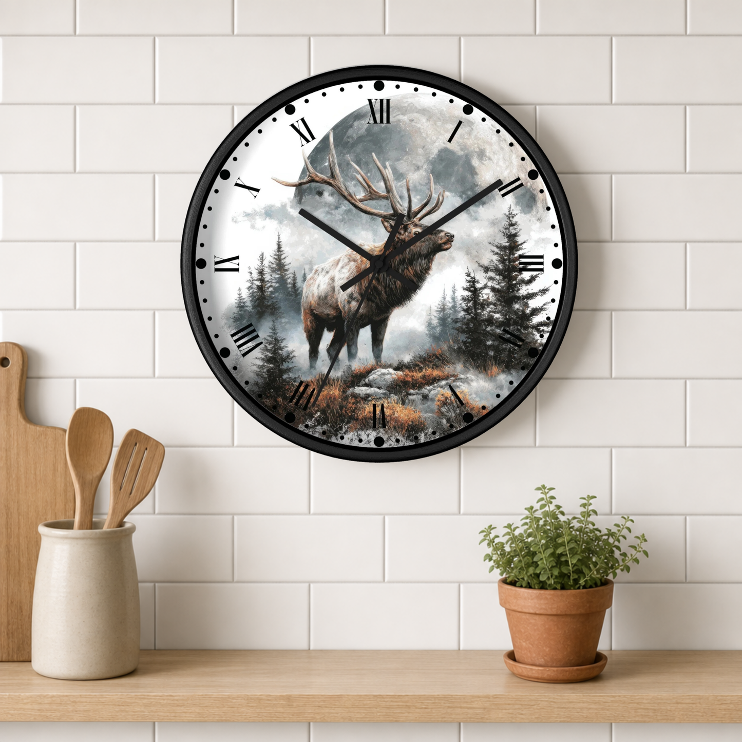 A round wall clock with a black frame hangs on a white subway tile wall above a wooden shelf. The clock face features a detailed illustration of a large elk standing in a misty pine forest.
