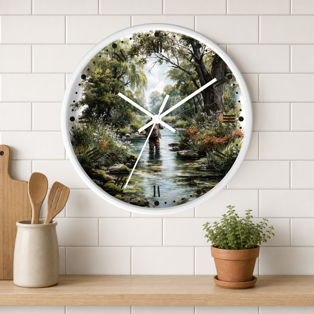 A round wall clock with a white frame and a scenic nature print of a person fishing in a stream, styled on a white subway tile wall above a wooden shelf with a small potted plant and wooden utensils.