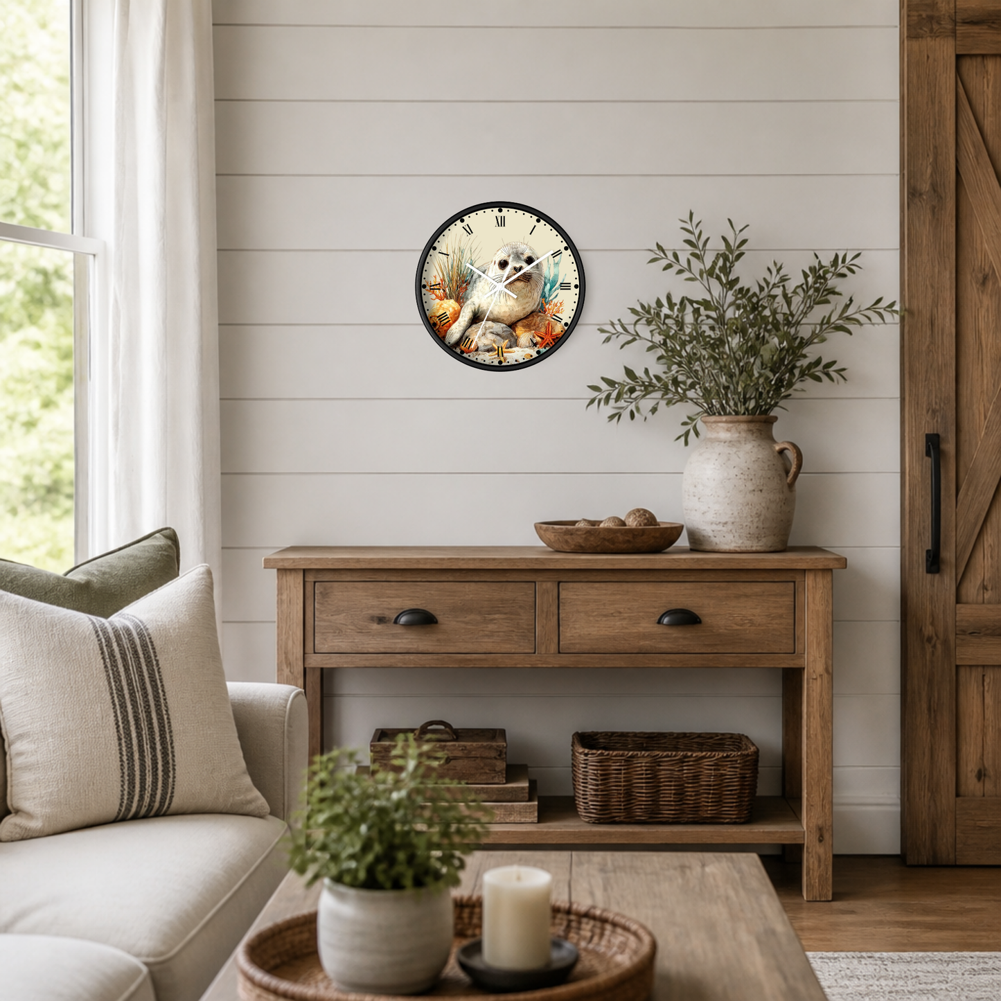 A round wall clock featuring a seal pup illustration, styled in a cozy, rustic living room setting above a wooden console table.