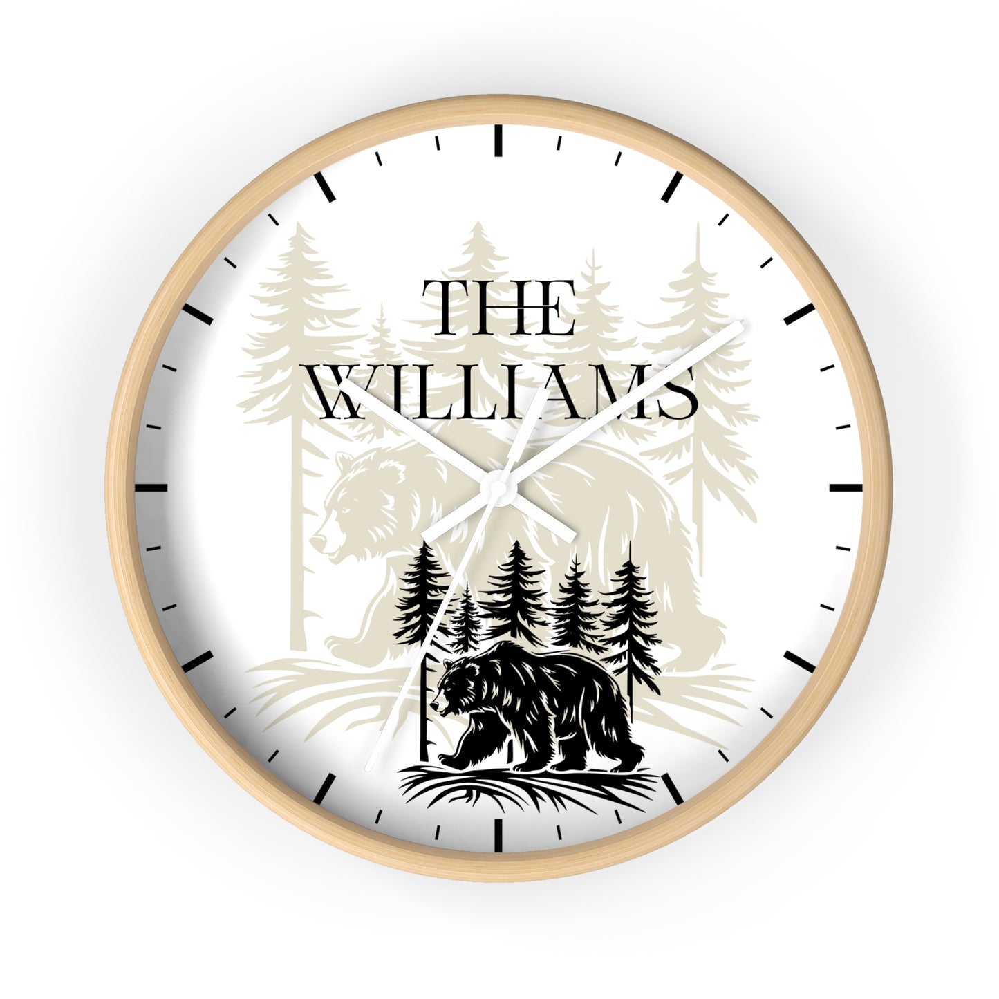 A personalized round wall clock with a light natural wood frame, featuring a white face with black hands and hour markers. The clock face is printed with a black bear silhouette, pine trees, and the text 'THE WILLIAMS' in a serif font.