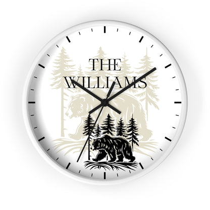 A round custom wall clock with a white face, black hands, and black hour markers. The dial features a personalized design with the text 'THE WILLIAMS' over a forest illustration, including a bear at the bottom.