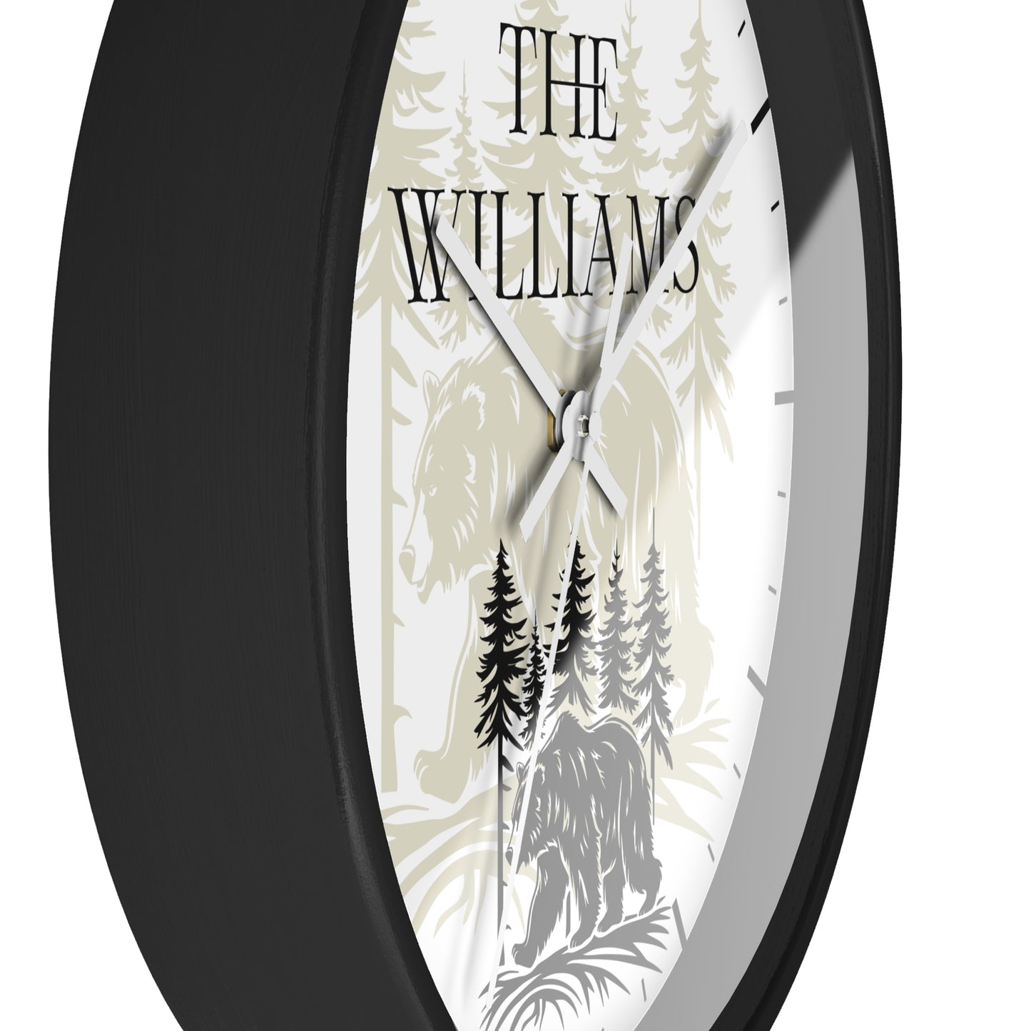 A close-up of a round wall clock with a black frame and a custom white dial featuring a forest design with the text 'THE WILLIAMS' and the names 'M. & J.