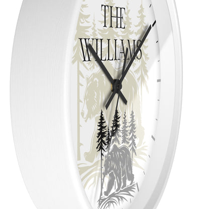 A close-up of a round wall clock with a white frame and a custom printed dial. The dial features a light beige forest illustration with a horse and bear, black hands, and the text 'THE WILLIAMS'.