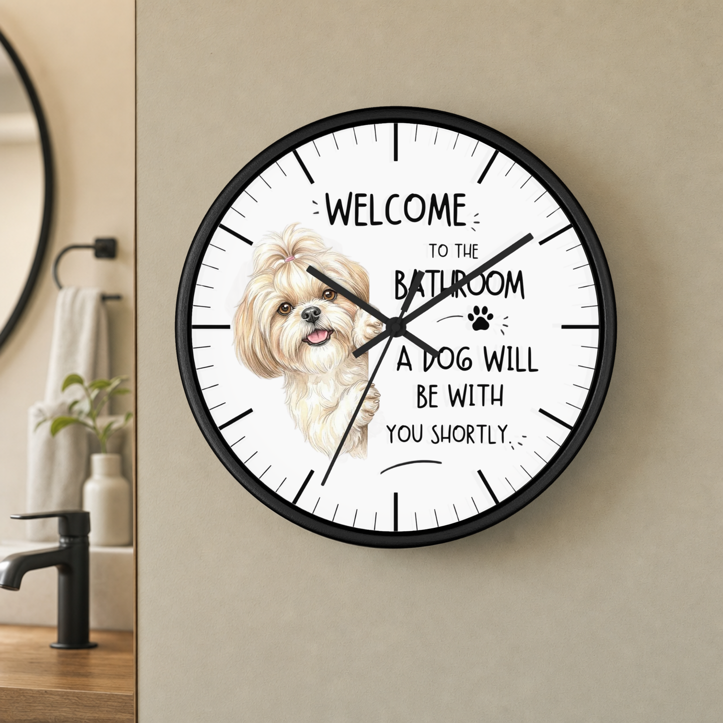 A round wall clock with a black frame and white face, featuring a fluffy cream-colored dog illustration and the text 'WELCOME TO THE BATHROOM A DOG WILL BE WITH YOU SHORTLY' in a bathroom setting.