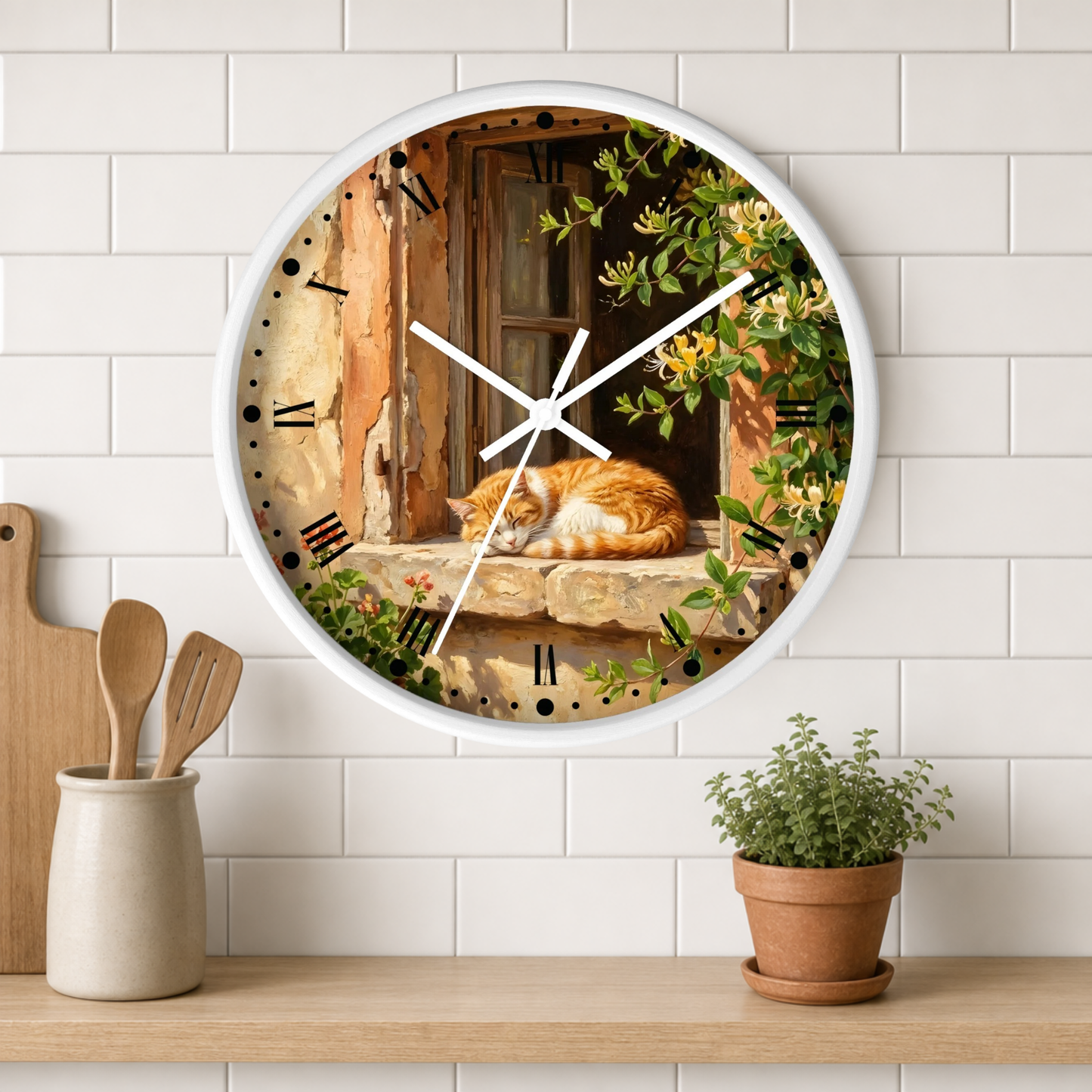 A round wall clock with a white frame hangs on a white subway tile wall above a wooden shelf. The clock face features a scenic illustration of an orange tabby cat sleeping on a stone windowsill with green ivy and yellow flowers.