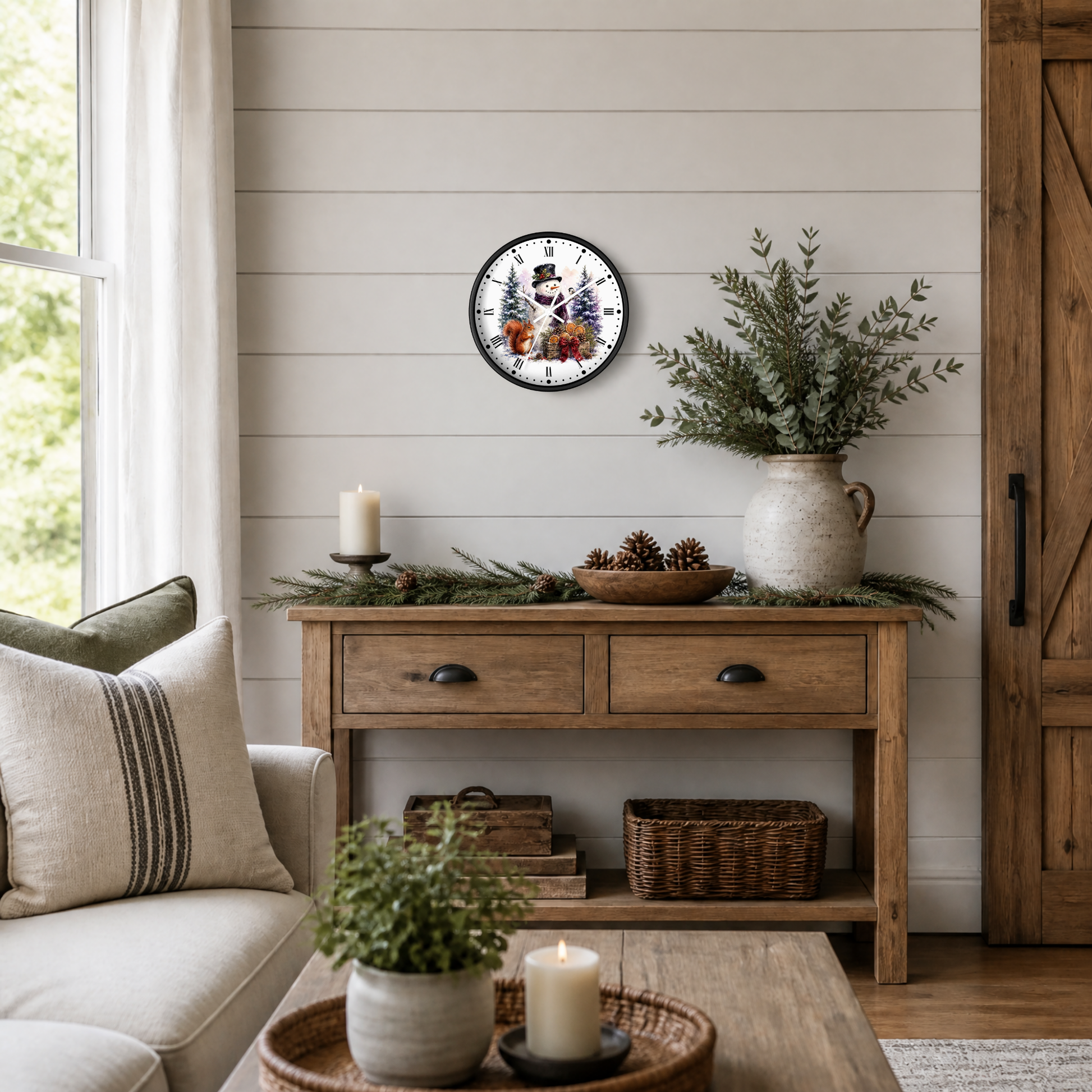 A round wall clock with a festive snowman and squirrel illustration and Roman numerals, styled on a shiplap wall above a rustic wooden console table in a cozy living room setting.