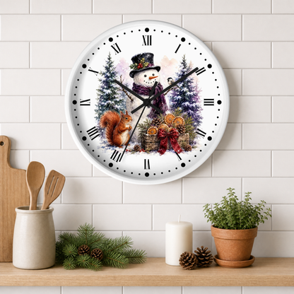 A round wall clock with a winter holiday illustration of a snowman, trees, a squirrel, and oranges, mounted on a white subway tile wall above a shelf with kitchen props.