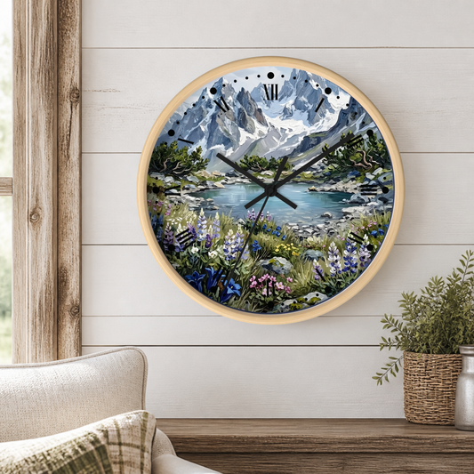 Round wall clock with a scenic mountain lake landscape print, mounted on a white wood-paneled wall above a wooden shelf with a plant and cushion visible.