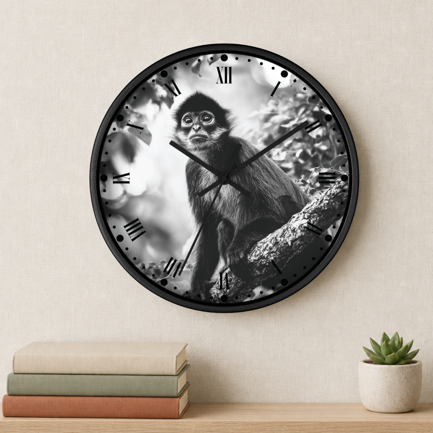 A round wall clock with a black frame and a black-and-white photo of a monkey on the clock face, mounted on a beige wall above a shelf with books and a small potted succulent.