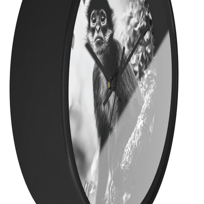 A round wall clock with a black frame and a black-and-white photographic print of a monkey on the face, shown against a plain white background.
