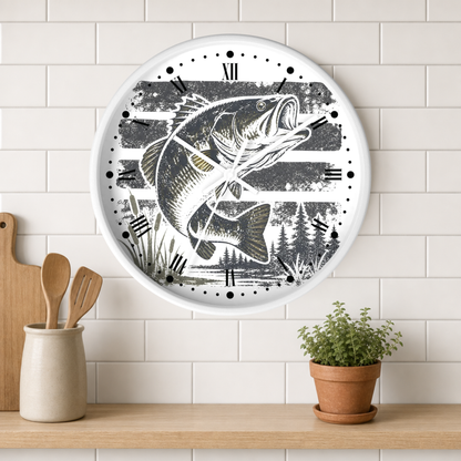A round wall clock with a white frame and a black-and-white fish illustration, mounted on a white subway tile wall above a wooden shelf with a small potted plant and kitchen utensils.