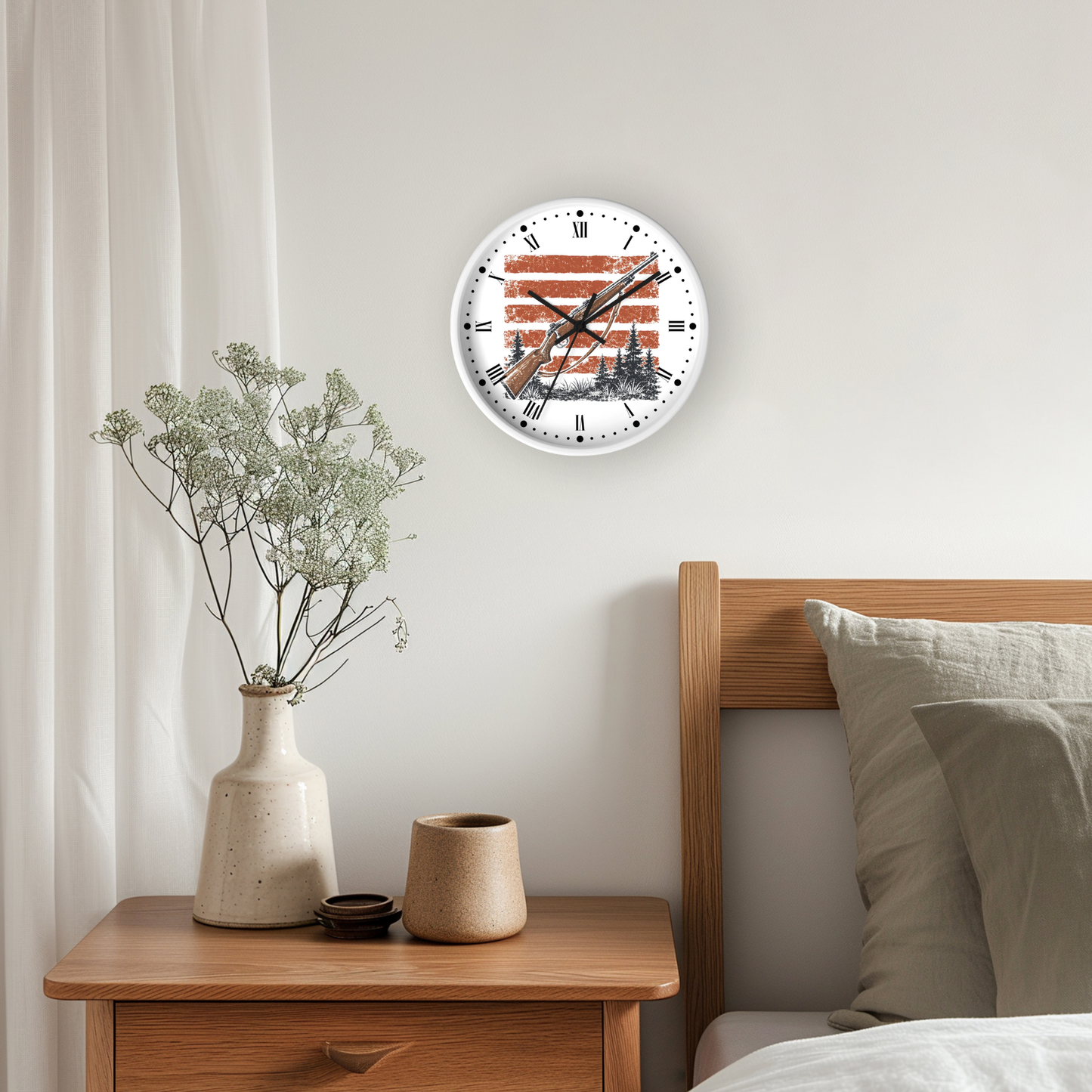 A round wall clock with a white face and black Roman numerals, featuring a red and black hunting rifle design, mounted on a light gray wall above a wooden headboard and bedside table.