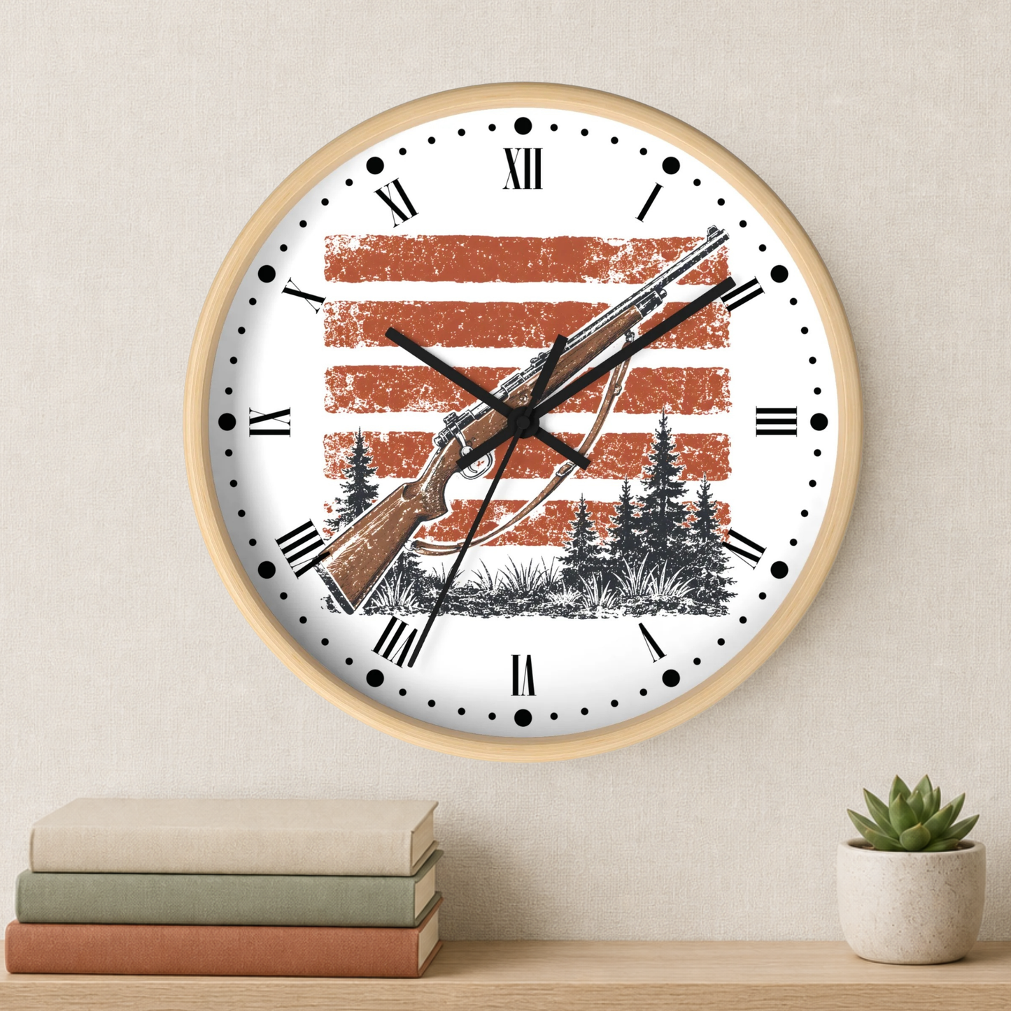 A round wall clock with a light wood frame hangs on a beige wall above a shelf with stacked books and a small potted succulent. The clock face is white with black Roman numerals and hands, featuring a distressed orange-red American flag background and a black-and-brown bowfishing illustration.