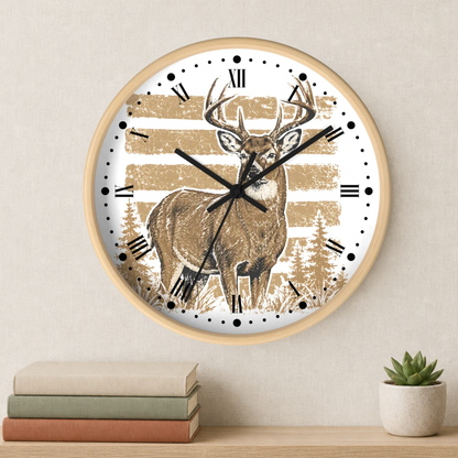 A round wall clock with a light wood frame hangs on a beige wall above a shelf with stacked books and a small potted succulent. The clock face features a brown deer illustration over a distressed tan and white striped background with black Roman numerals and black clock hands.