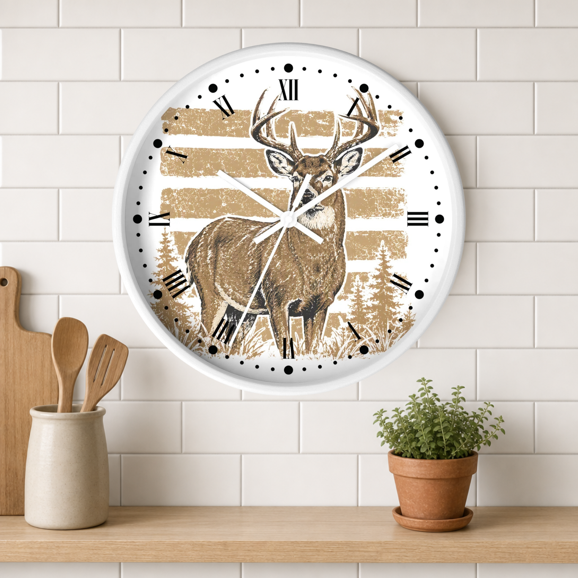 A round wall clock with a white frame hangs on a white subway tile wall above a wooden shelf. The clock face features a brown deer with antlers standing in front of tan horizontal stripes and pine trees.