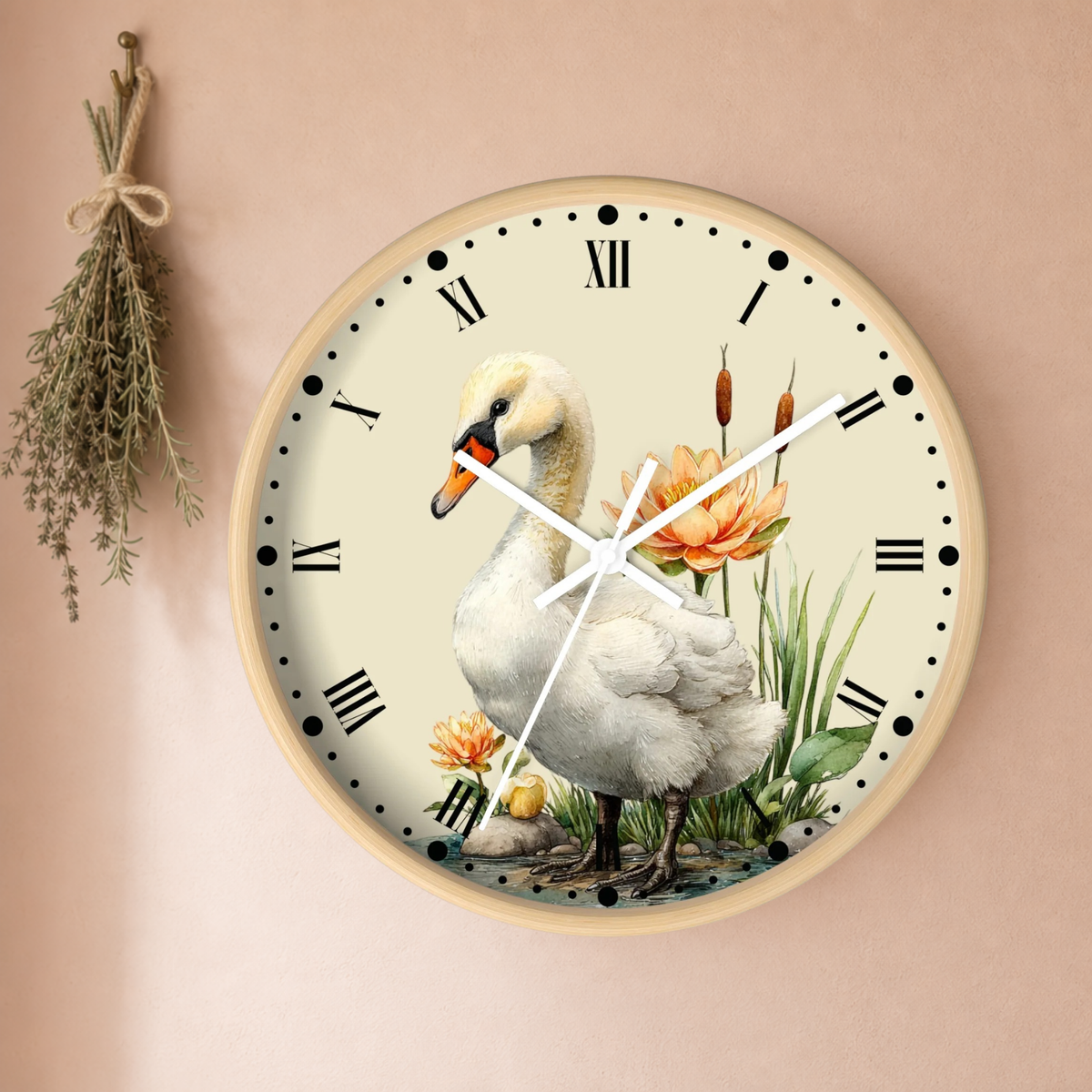Round wall clock with a natural wood frame and a cream dial featuring a white swan, orange flowers, green reeds, and black Roman numerals, mounted on a warm beige wall with a dried herb sprig hanging to the left.