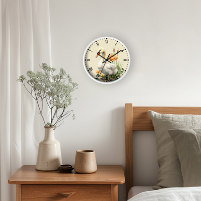 A round wall clock with a white face and black Roman numerals hangs on a light gray bedroom wall above a wooden nightstand. The clock face features a printed illustration of a white duckling in a pond with orange accents.
