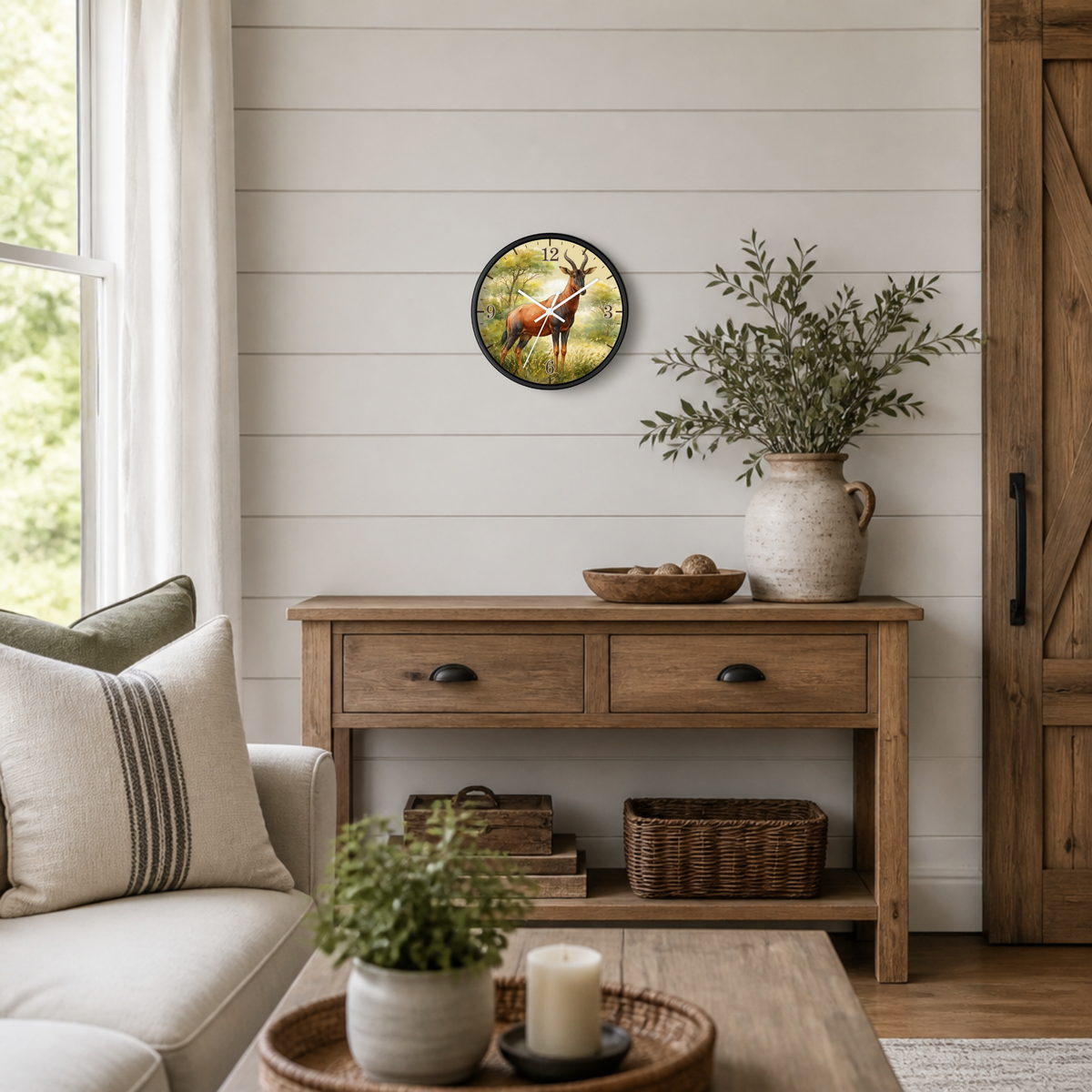 A round wall clock featuring a deer in a forest, styled on a white shiplap wall above a rustic wooden console table in a bright, modern living room.