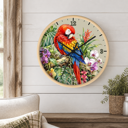 A round wall clock with a light wood frame hangs on a white shiplap wall above a wooden console table. The clock face features a colorful illustration of a red, yellow, and blue parrot perched among green tropical leaves and purple and white flowers.