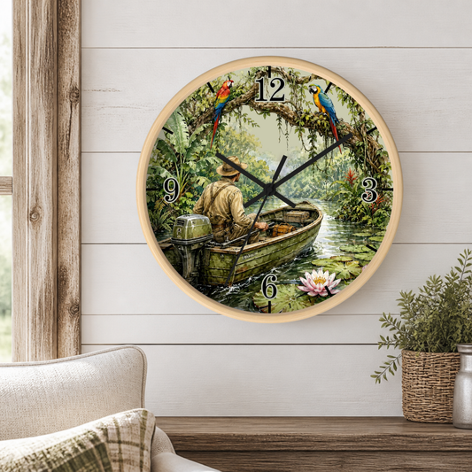 A round wall clock with a light wood frame hangs on a white shiplap wall above a wooden table. The clock face features a scenic illustration of a man rowing in a small boat on a river, surrounded by lush green foliage, colorful parrots, and a pink lotus flower.