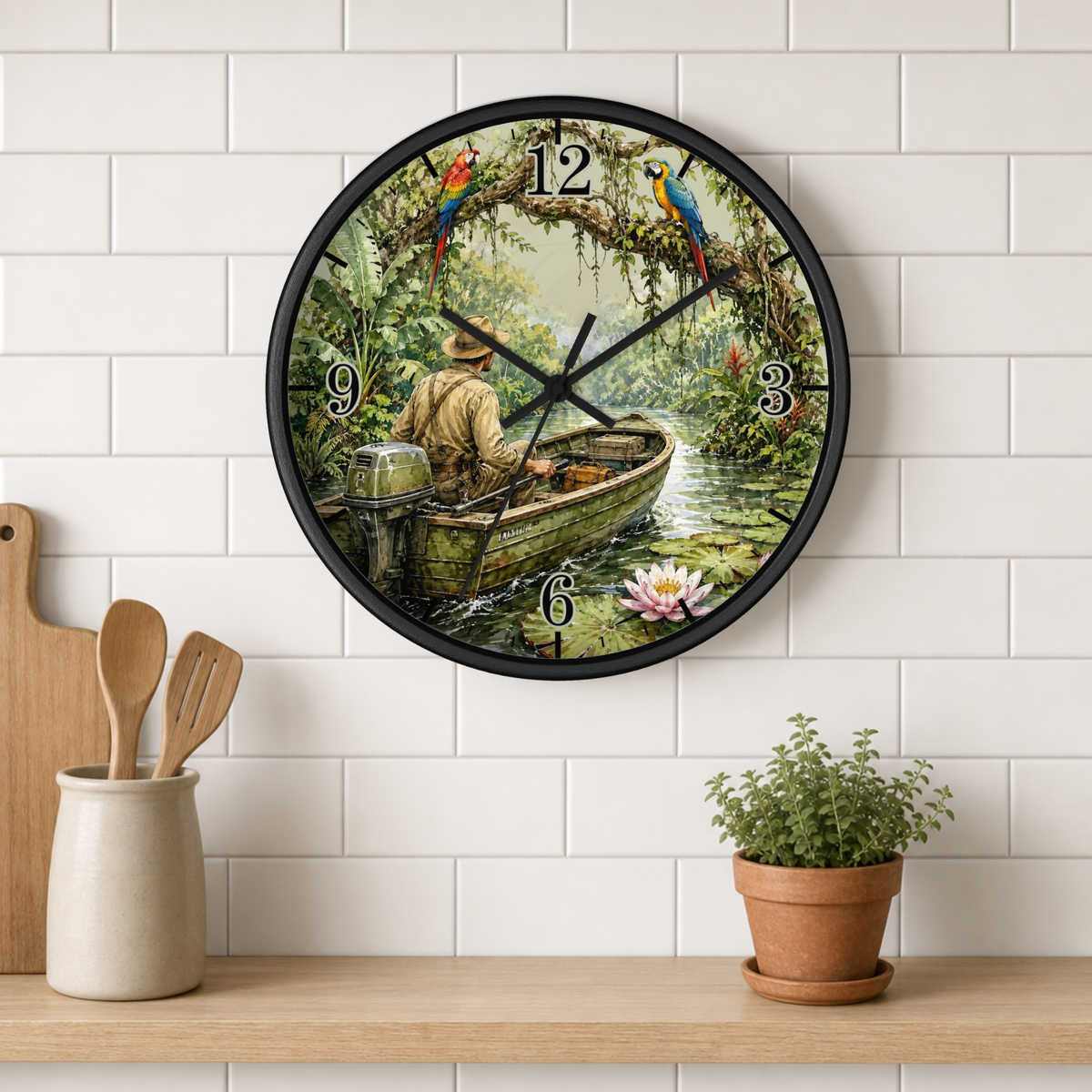 A round wall clock with a black frame and a tropical jungle scene printed on the face, hanging on a white subway tile wall above a wooden shelf with kitchen utensils and a potted plant.