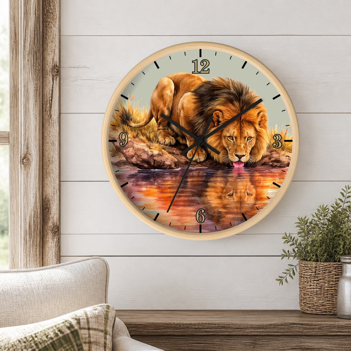 A round wall clock featuring a realistic lion painting on the face, hanging on a white wood-paneled wall above a wooden table with a potted plant and part of a sofa visible.
