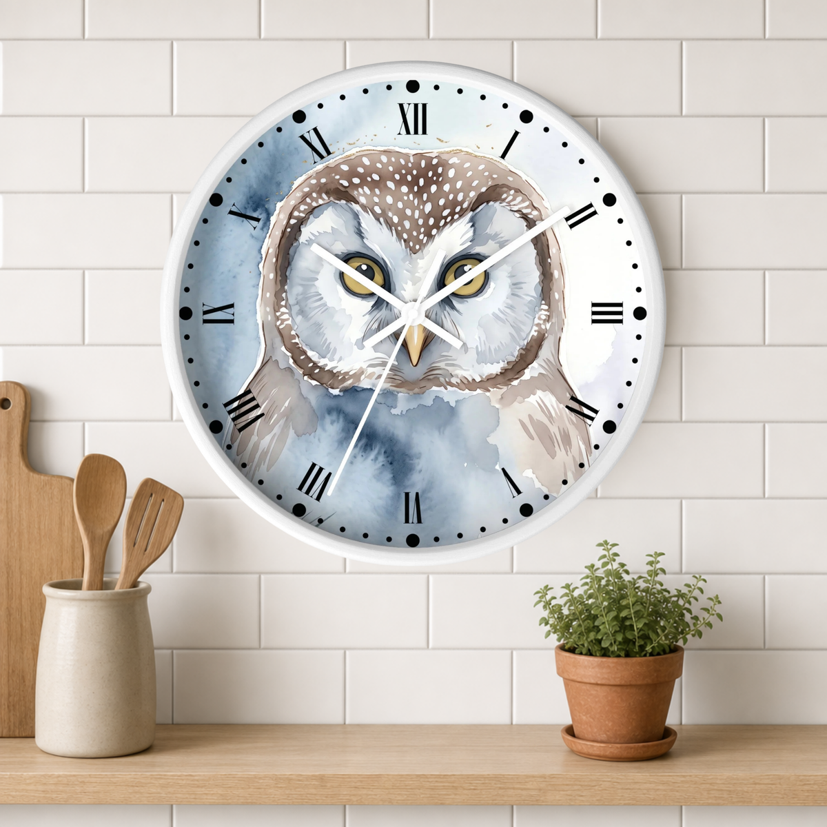 A round wall clock with a watercolor-style owl illustration, mounted on a white subway-tile wall above a wooden shelf with kitchen utensils and a small potted plant.