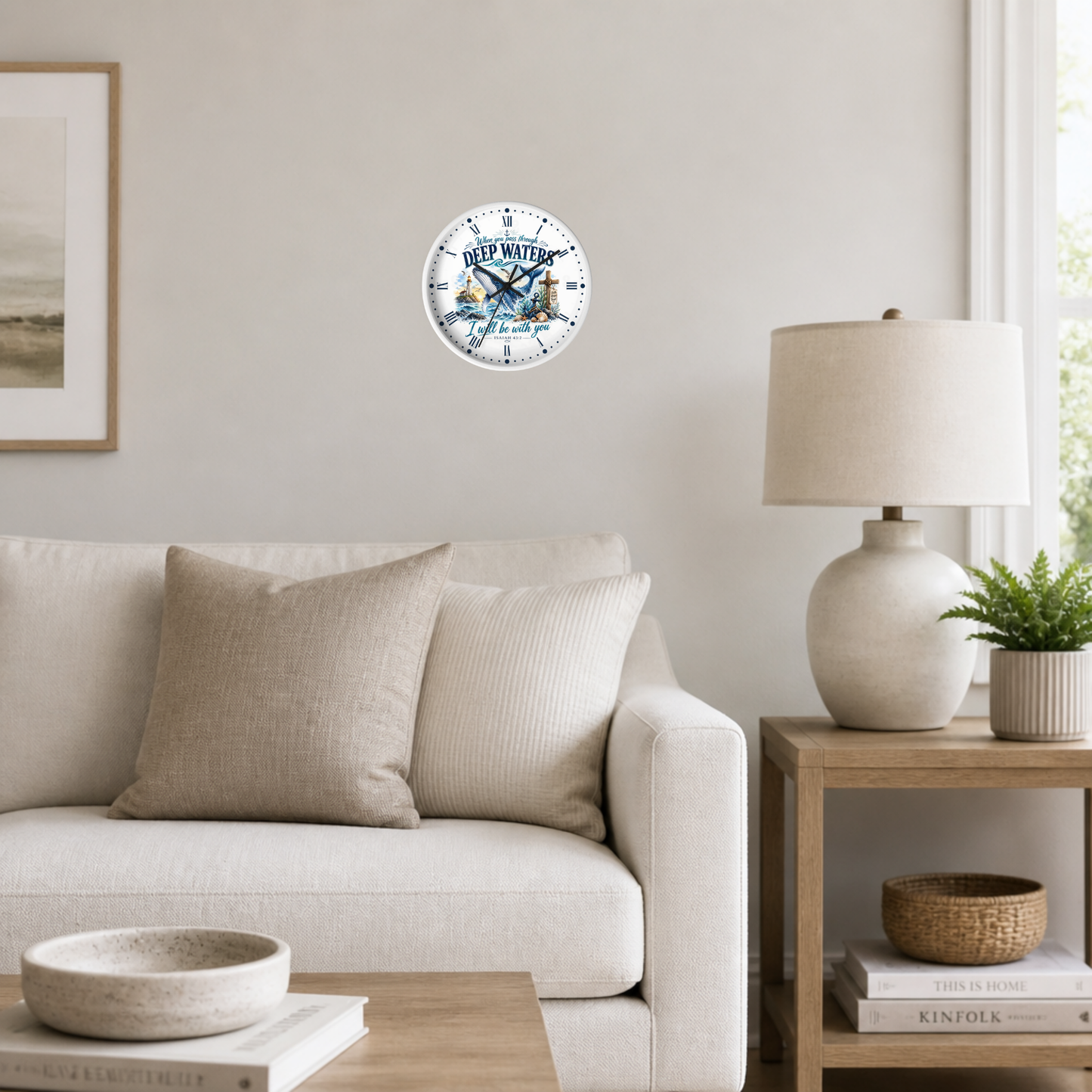A round wall clock featuring a vintage illustration of a whale and the text 'When you pass through deep waters, i shall be with you', mounted on a light gray wall in a modern living room setting.