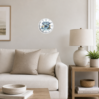 A round wall clock featuring a vintage illustration of a whale and the text 'When you pass through deep waters, i shall be with you', mounted on a light gray wall in a modern living room setting.