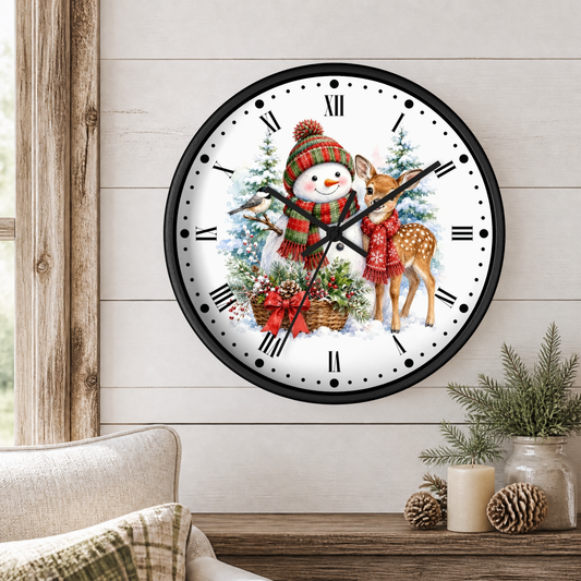 A round wall clock with a black frame and a festive Christmas illustration on the face, hanging on a light wood paneled wall above a table with candles and pine branches.