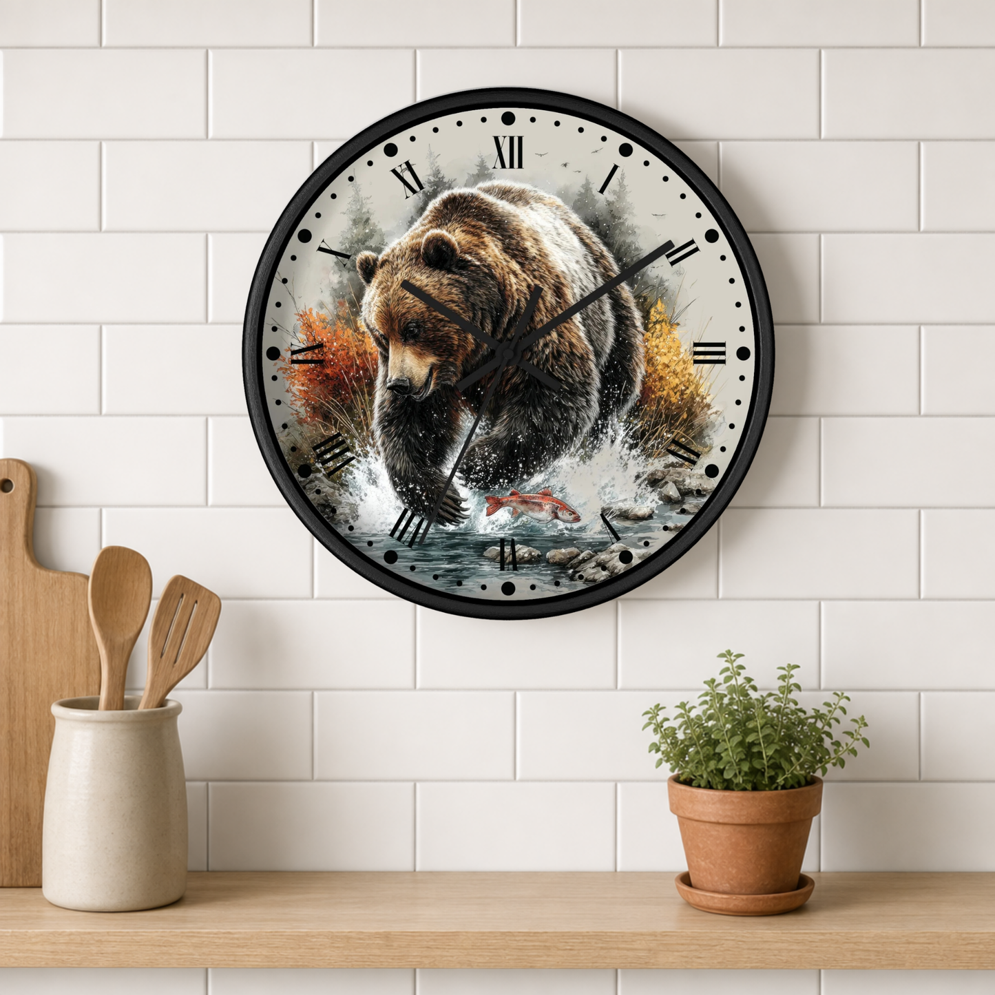 A round wall clock with a black frame hangs on a white subway tile wall above a wooden shelf. The clock face features a detailed illustration of a brown bear swimming in water with fish and autumn leaves.