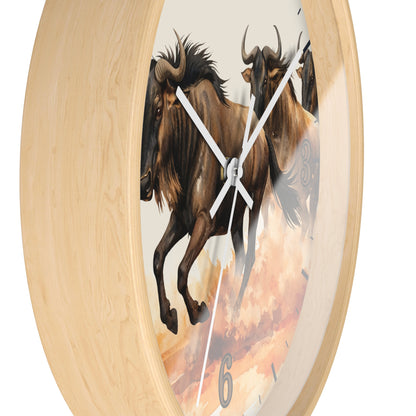 A round wall clock with a light natural wood frame and a printed face showing two brown wildebeest against a warm sky background. The clock has white hands and a thin second hand, with the number 6 visible near the bottom.