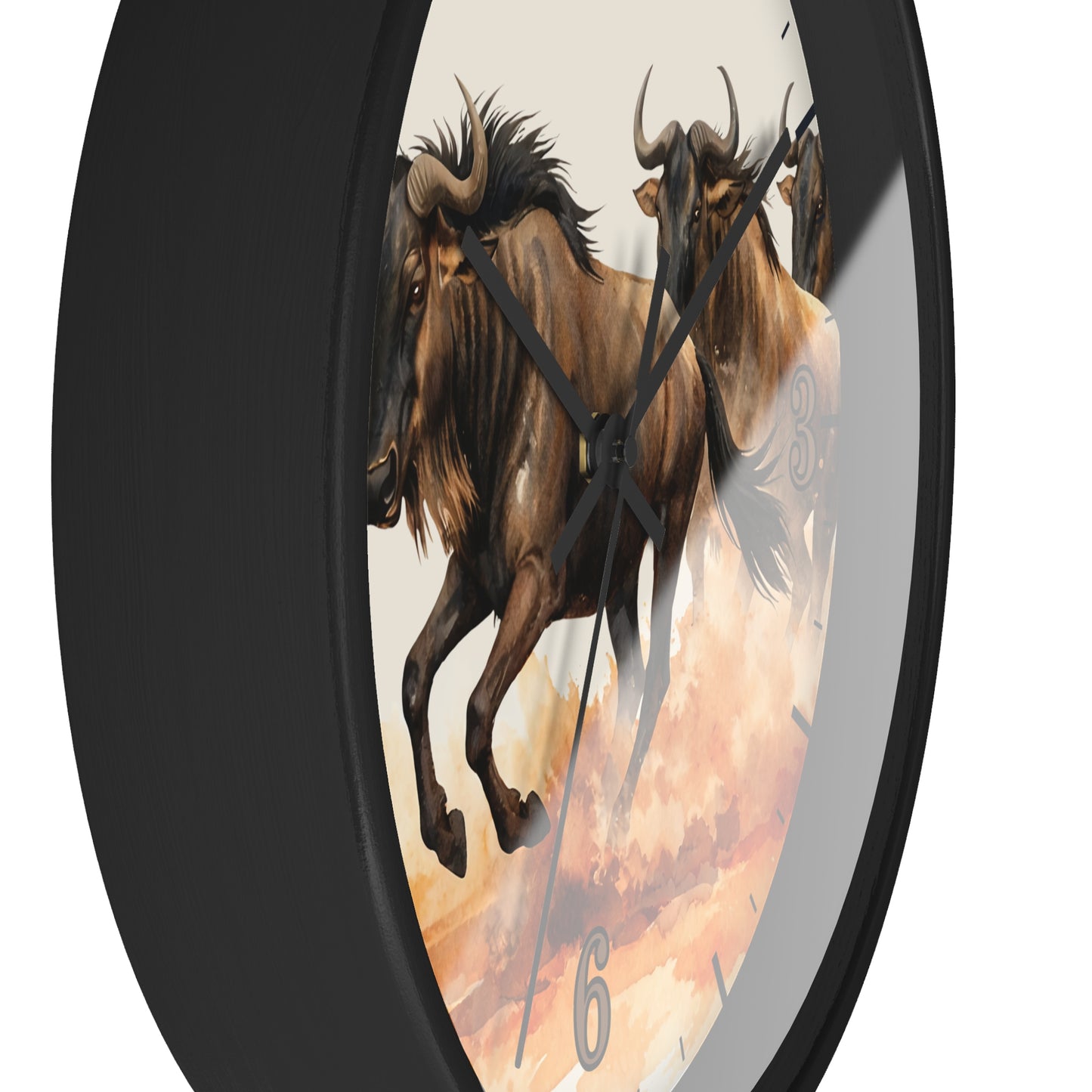 Round wall clock with a black frame and a printed face showing two brown wildebeest against a warm cream and orange sky. The clock is photographed at an angle on a plain white background.