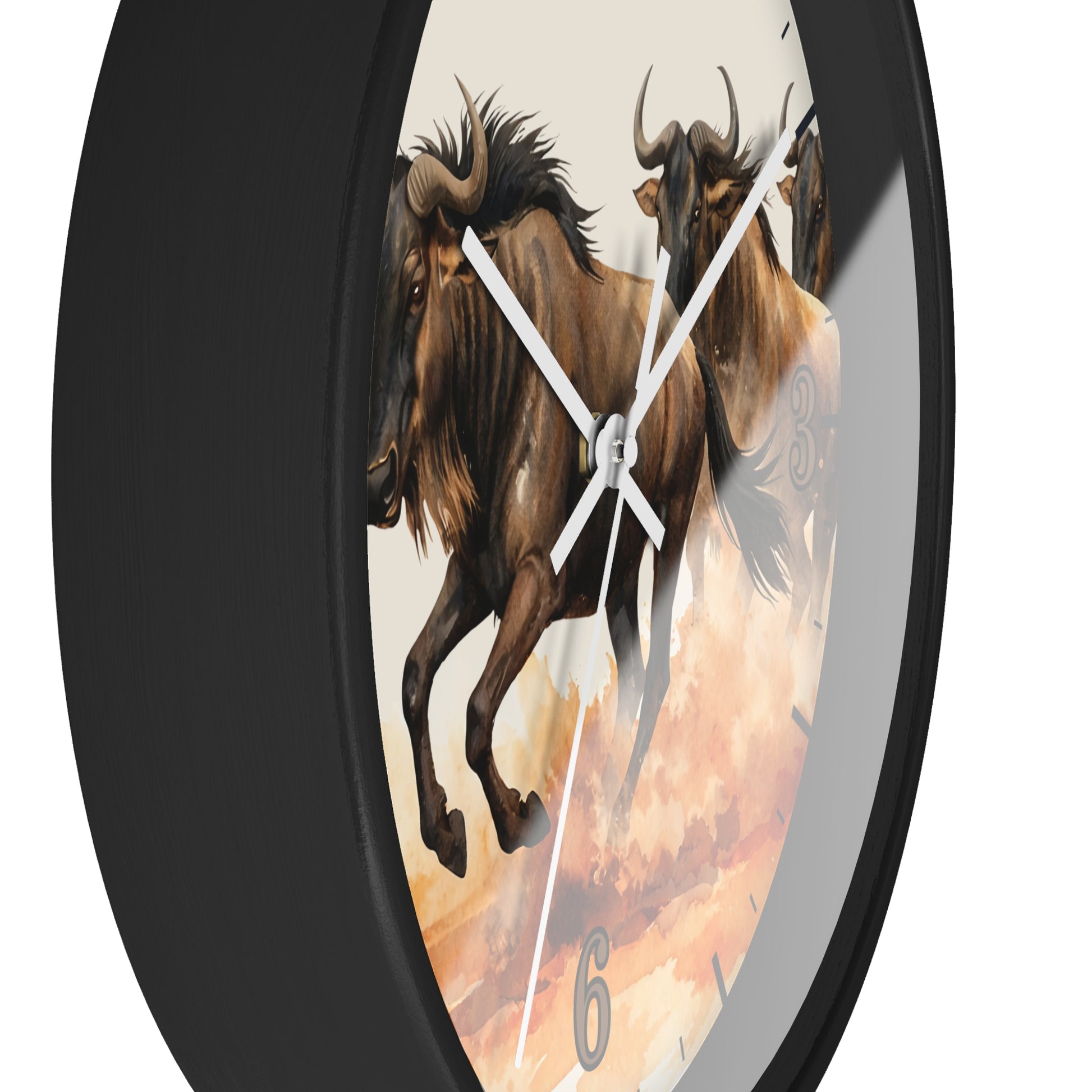 A round wall clock with a black frame and a printed face showing two brown wildebeest against a warm beige and orange sky. The clock has white hands and a visible second hand, photographed on a plain white background.