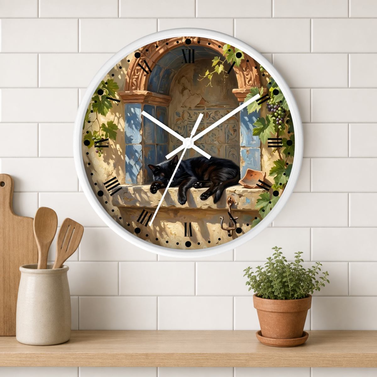 A round wall clock with a white frame hangs on a white subway-tile wall above a wooden shelf. The clock face features a vintage-style illustration of a black cat sleeping on a stone windowsill with Roman numerals, white clock hands, and green ivy details.
