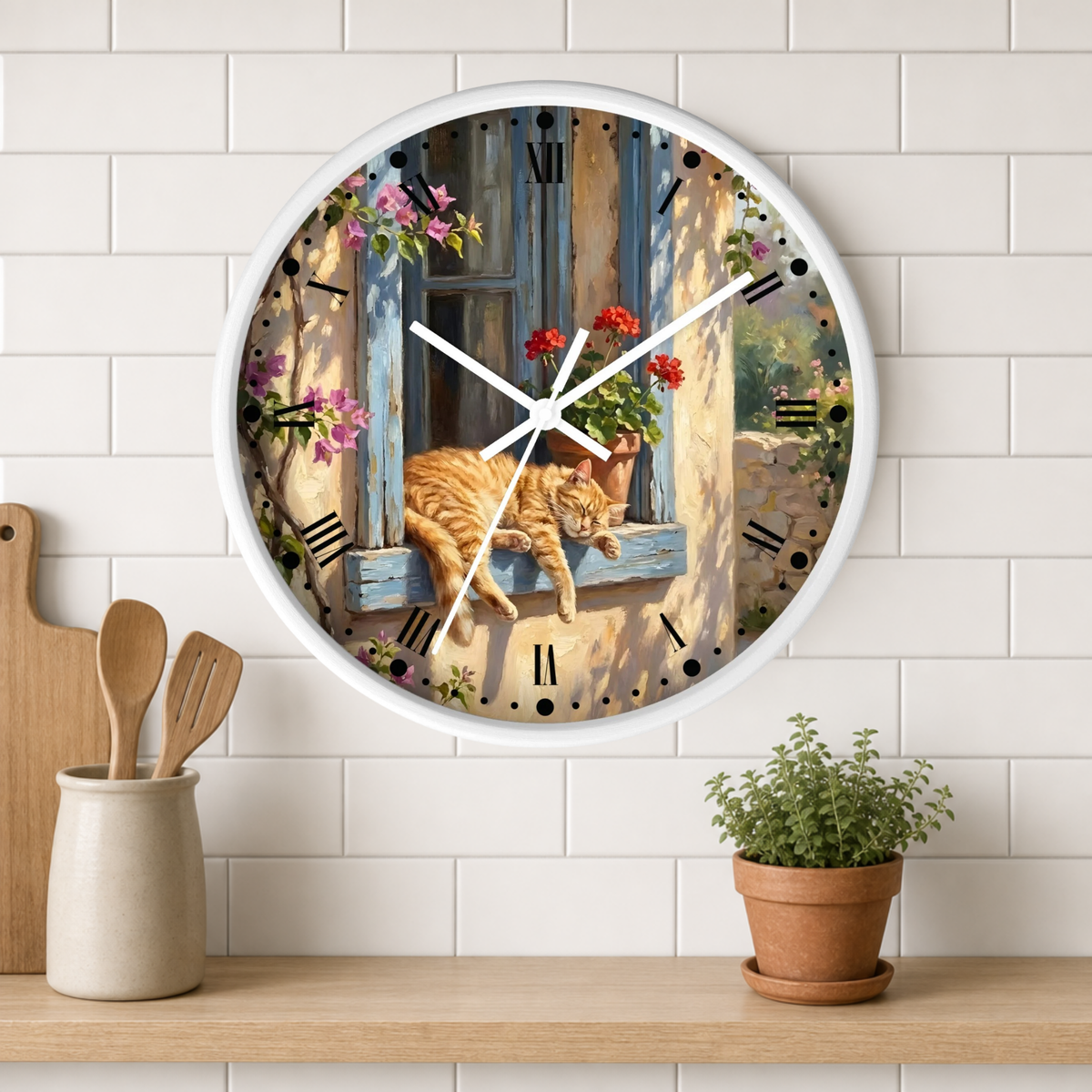 A round wall clock with a white frame hangs on a white subway tile wall above a wooden shelf. The clock face features a colorful illustration of an orange tabby cat lying on a blue window sill with pink and red flowers, set against a rustic sunlit wall.