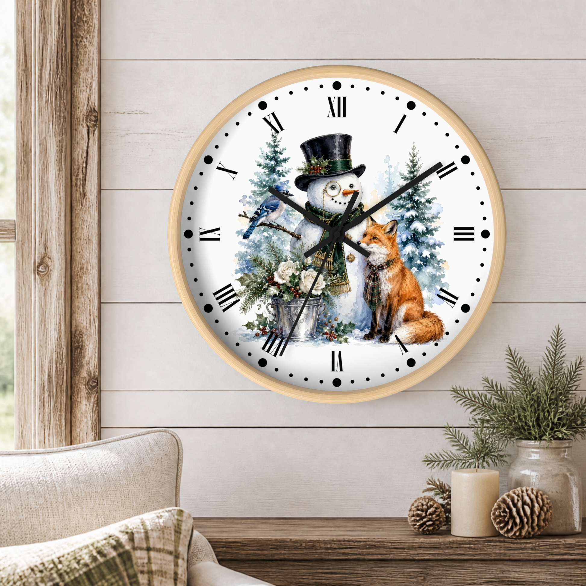 A round wall clock with a light wood frame hangs on a white shiplap wall above a rustic wooden table. The clock face features a winter illustration with a snowman in a top hat, a bluebird, a fox, evergreen trees, and black Roman numerals.
