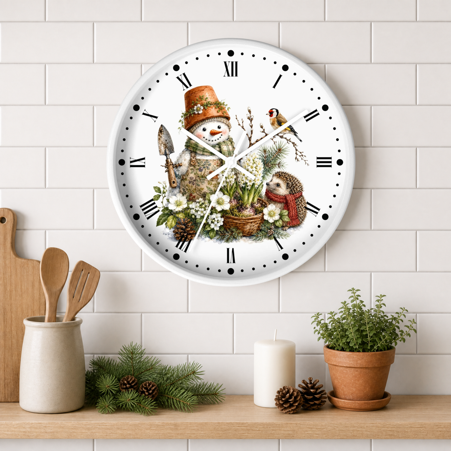 A round white wall clock with a whimsical winter garden illustration, featuring a snowman in a top hat, a bird, and vegetables, mounted on a white subway tile wall above a wooden shelf with decorative items.