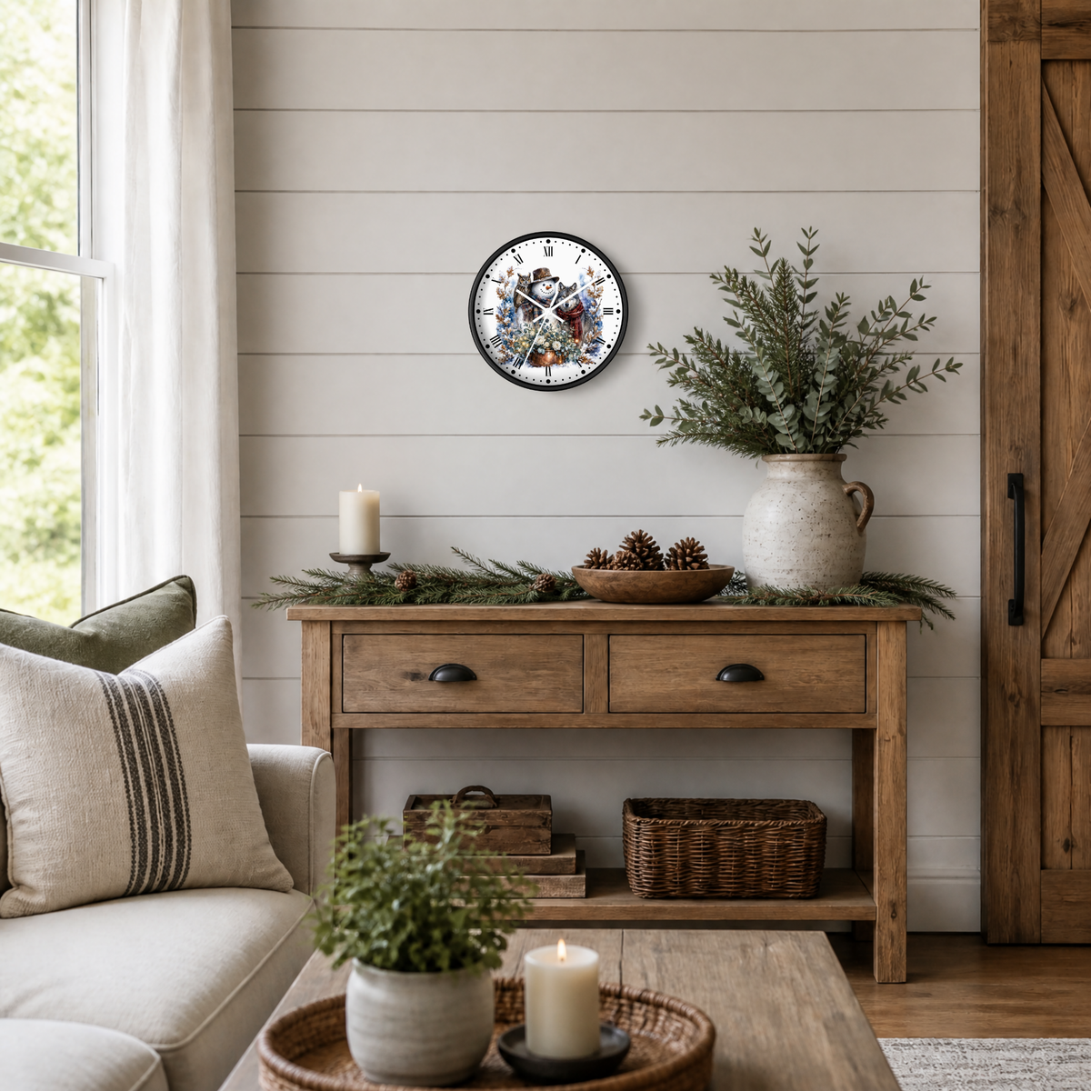 A round wall clock with a festive snowman, owl, and wolf illustration and Roman numerals, styled on a shiplap wall above a rustic wooden console table in a cozy living room setting.