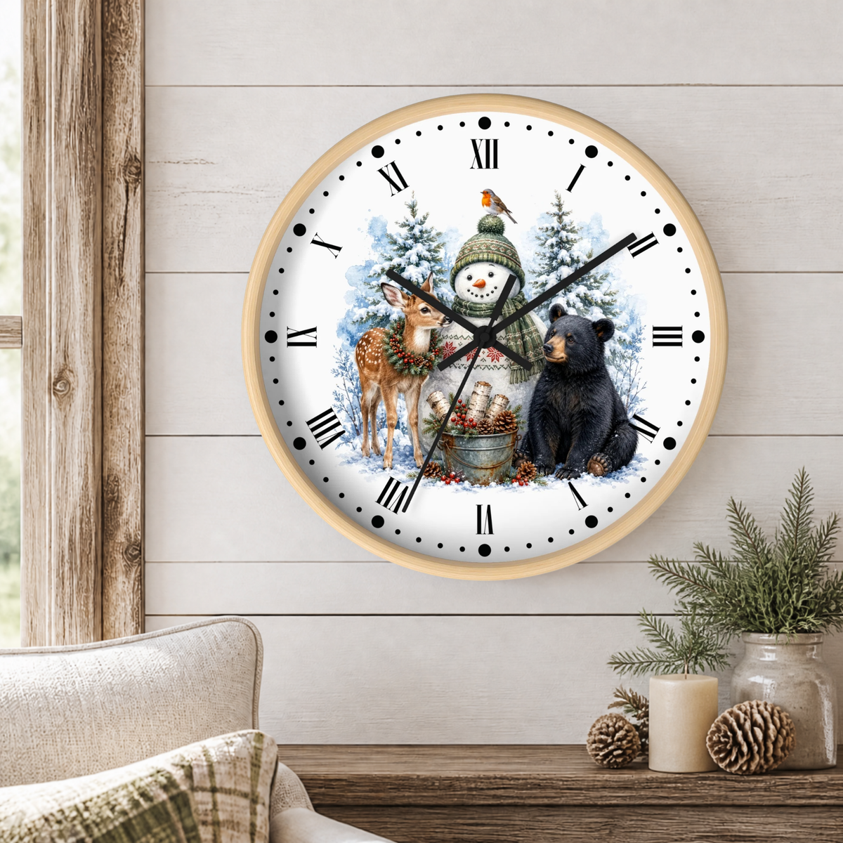 A round wall clock with a light wood frame hangs on a white shiplap wall above a rustic wooden table. The clock face features a winter holiday illustration with a snowman, a deer, a bear, and a bird, with black Roman numerals and hands.