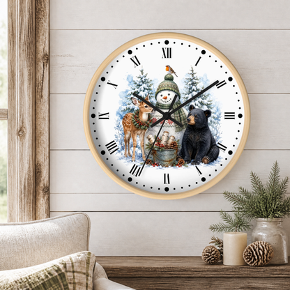 A round wall clock with a light wood frame hangs on a white shiplap wall above a rustic wooden table. The clock face features a winter holiday illustration with a snowman, a deer, a bear, and a bird, with black Roman numerals and hands.
