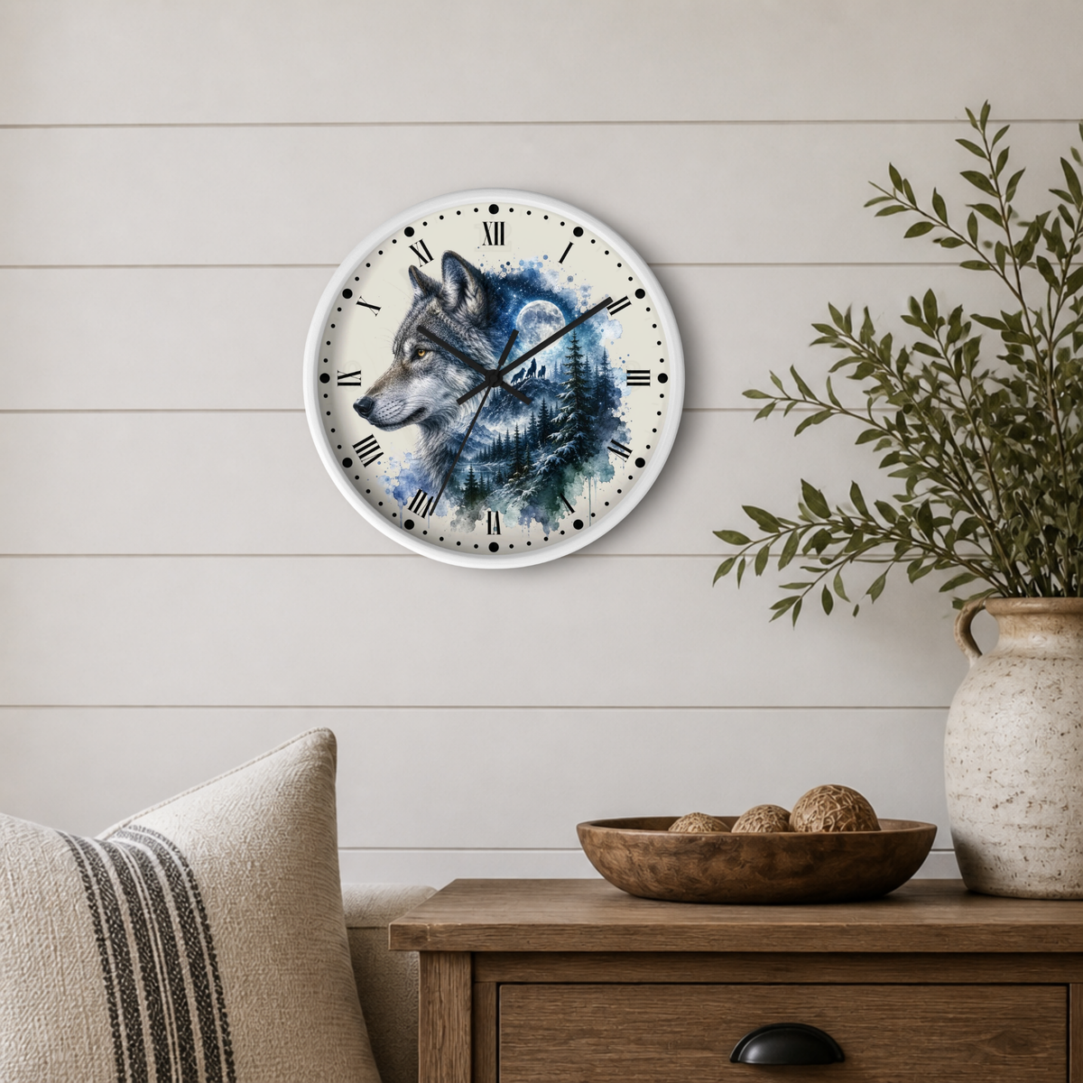 A round wall clock with a watercolor wolf design in blue, gray, and black tones, mounted on a light beige shiplap wall above a wooden side table with a vase and bowl.