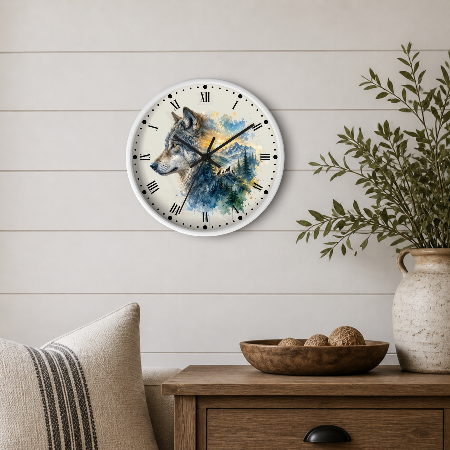 A round wall clock with a watercolor wolf illustration on the face, mounted on a light beige shiplap wall above a wooden side table with a plant and decorative bowl.