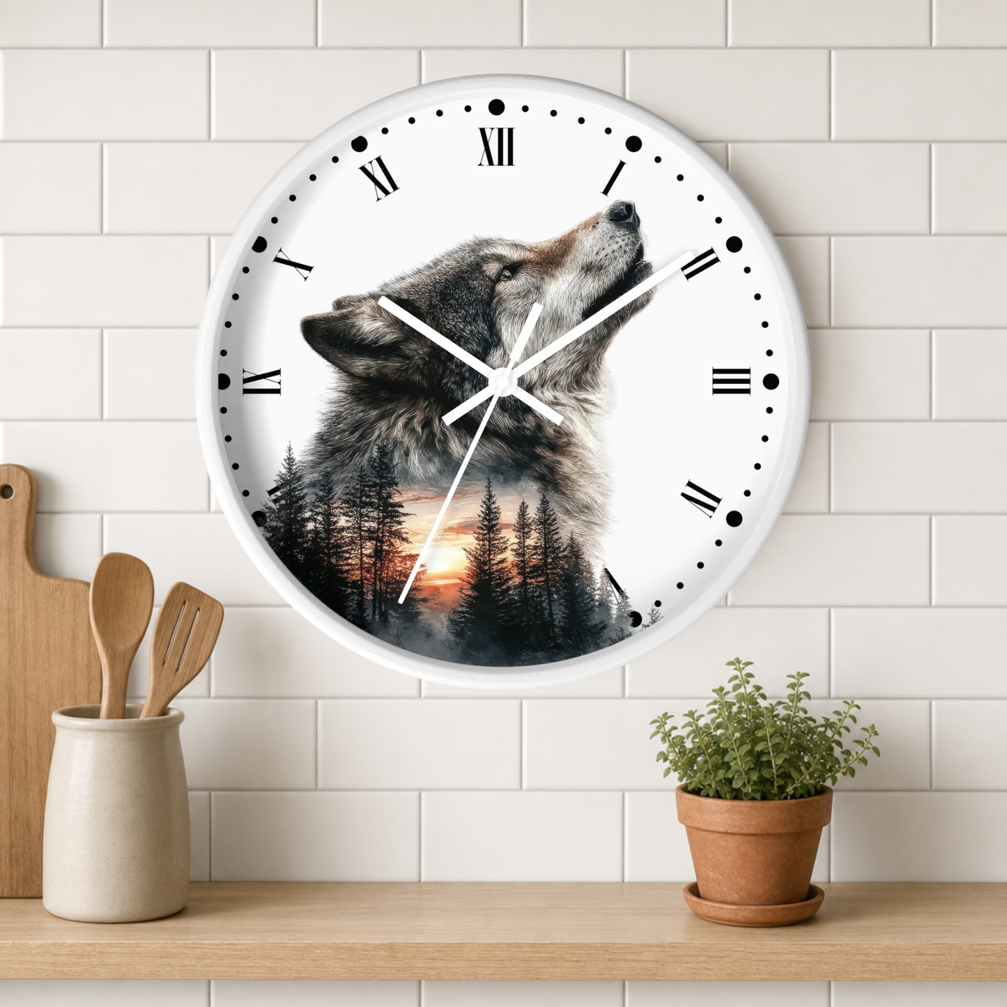 A round wall clock with a white face and black Roman numerals, featuring a printed design of a howling wolf over a pine forest at sunset. The clock is mounted on a white subway tile wall above a wooden shelf with a small potted plant and wooden utensils.