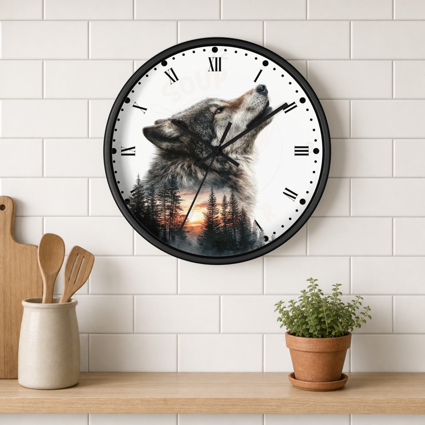 A round wall clock with a black frame hangs on a white subway-tile kitchen wall above a wooden shelf. The clock face features a wolf howling at sunset with a forest silhouette overlay.