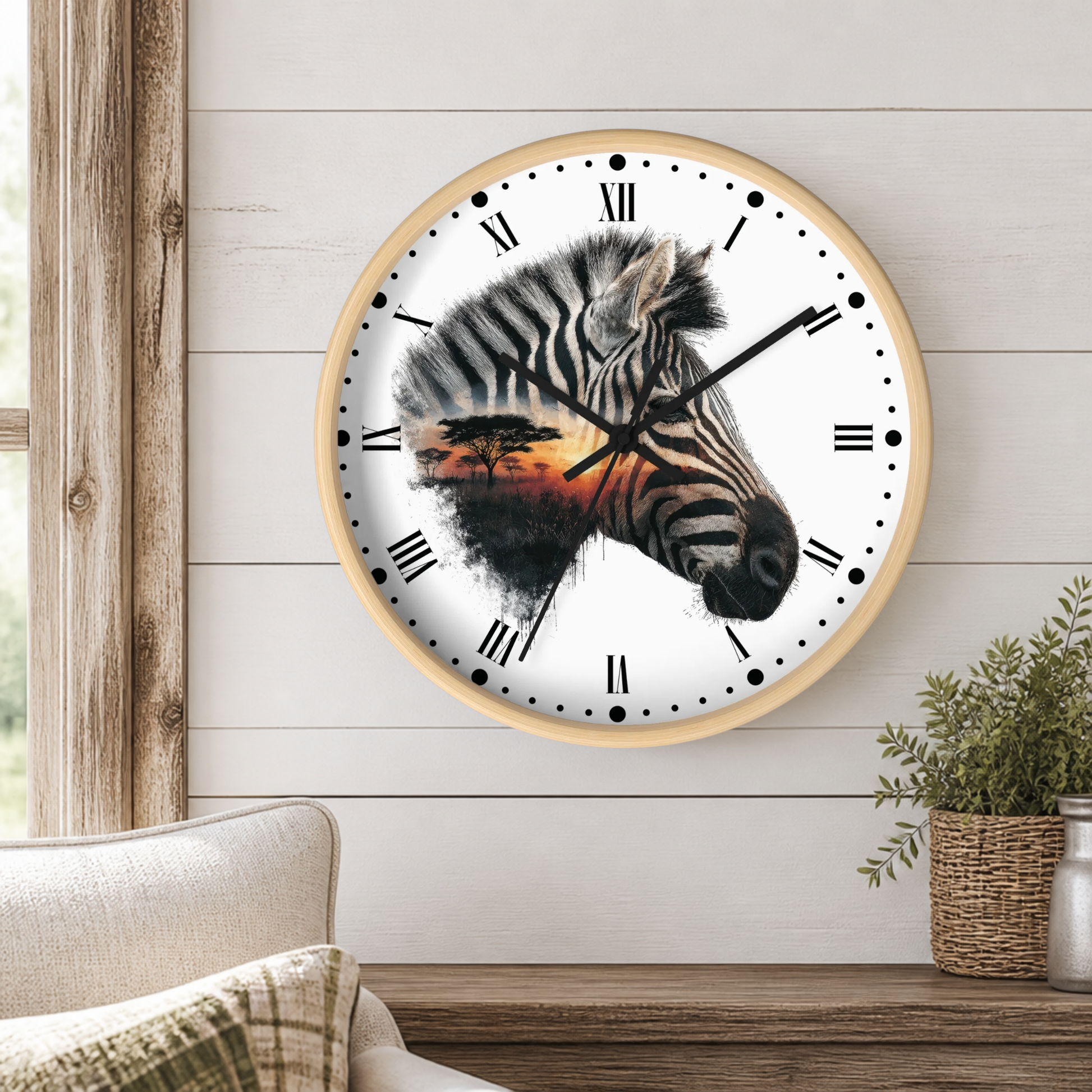 A round wall clock with a light wood frame and a white face, featuring a zebra head design with a sunset landscape inside. The clock is mounted on a white shiplap wall above a wooden mantel with a small potted plant.